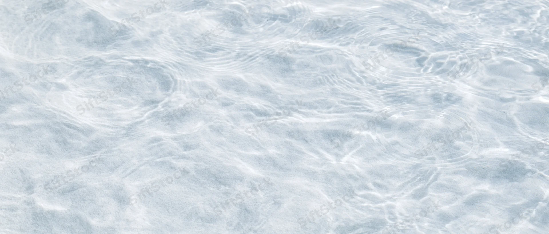 Rippling water surface with light reflections and gentle waves in shallow clear water