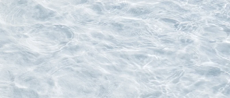Rippling water surface with light reflections and gentle waves in shallow clear water