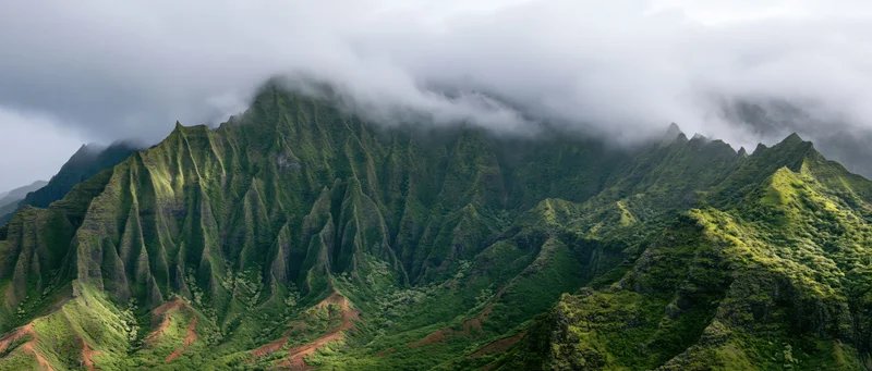 Rugged green mountain peaks rising from a misty valley with dense tropical vegetation