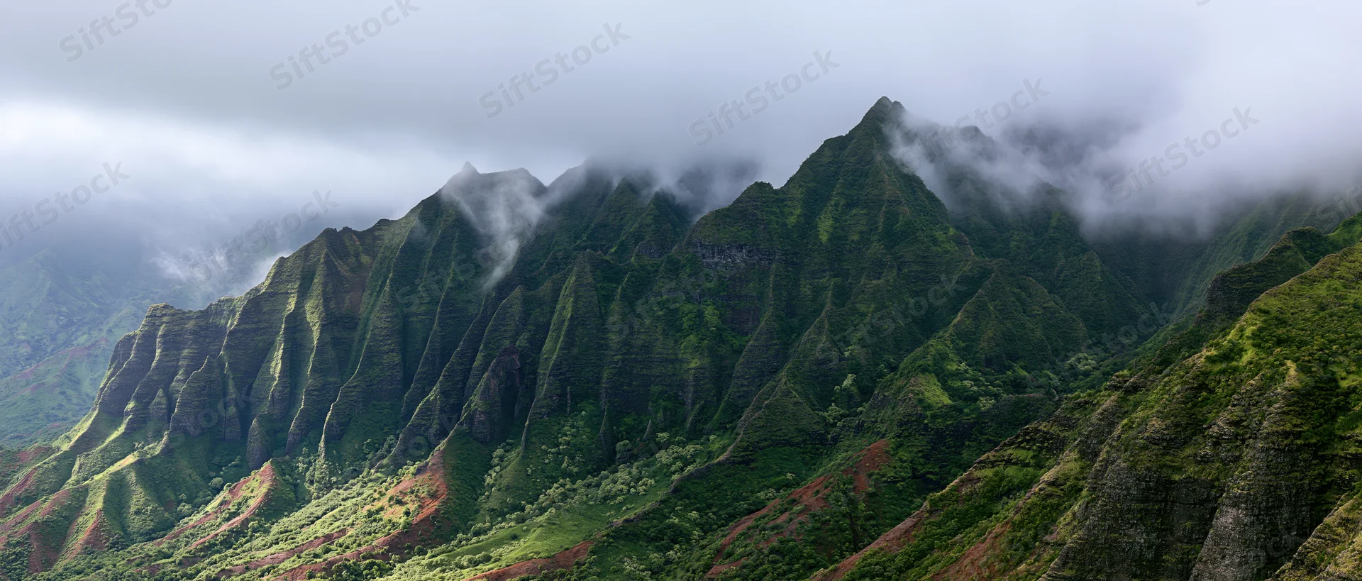 Rugged green mountain ridges rising from a misty valley in a tropical rainforest landscape