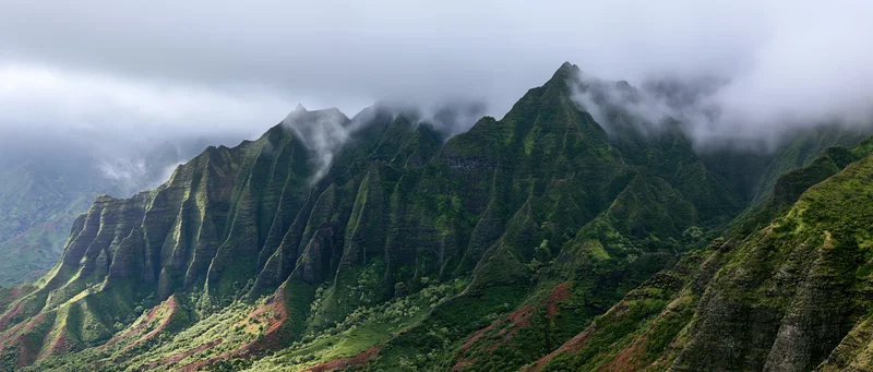 Rugged green mountain ridges rising from a misty valley in a tropical rainforest landscape