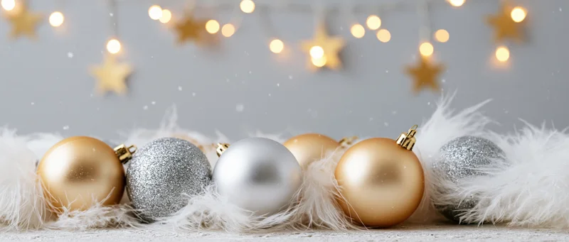 Christmas ornaments arranged on white feathers with blurred star lights in background