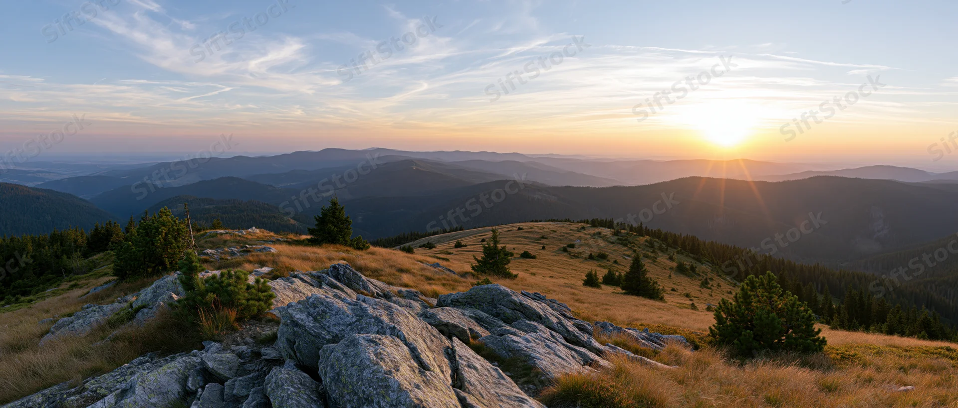 Mountain ridge at sunrise overlooking layered valleys and forests