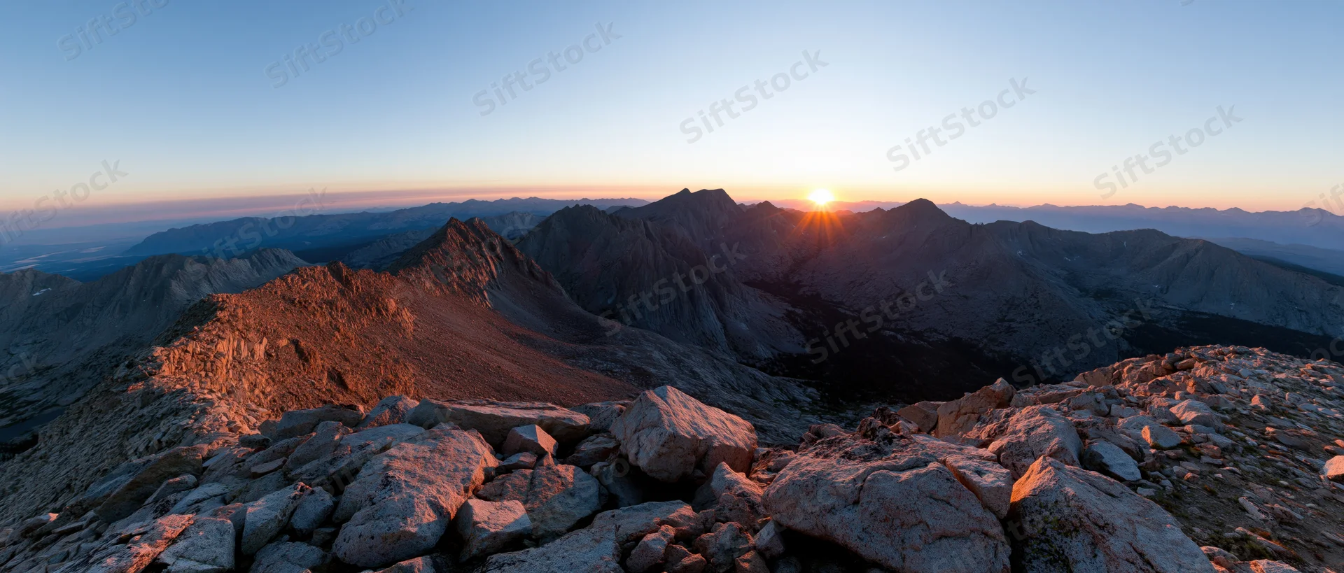 Sunrise over rugged mountain peaks and rocky terrain in alpine landscape