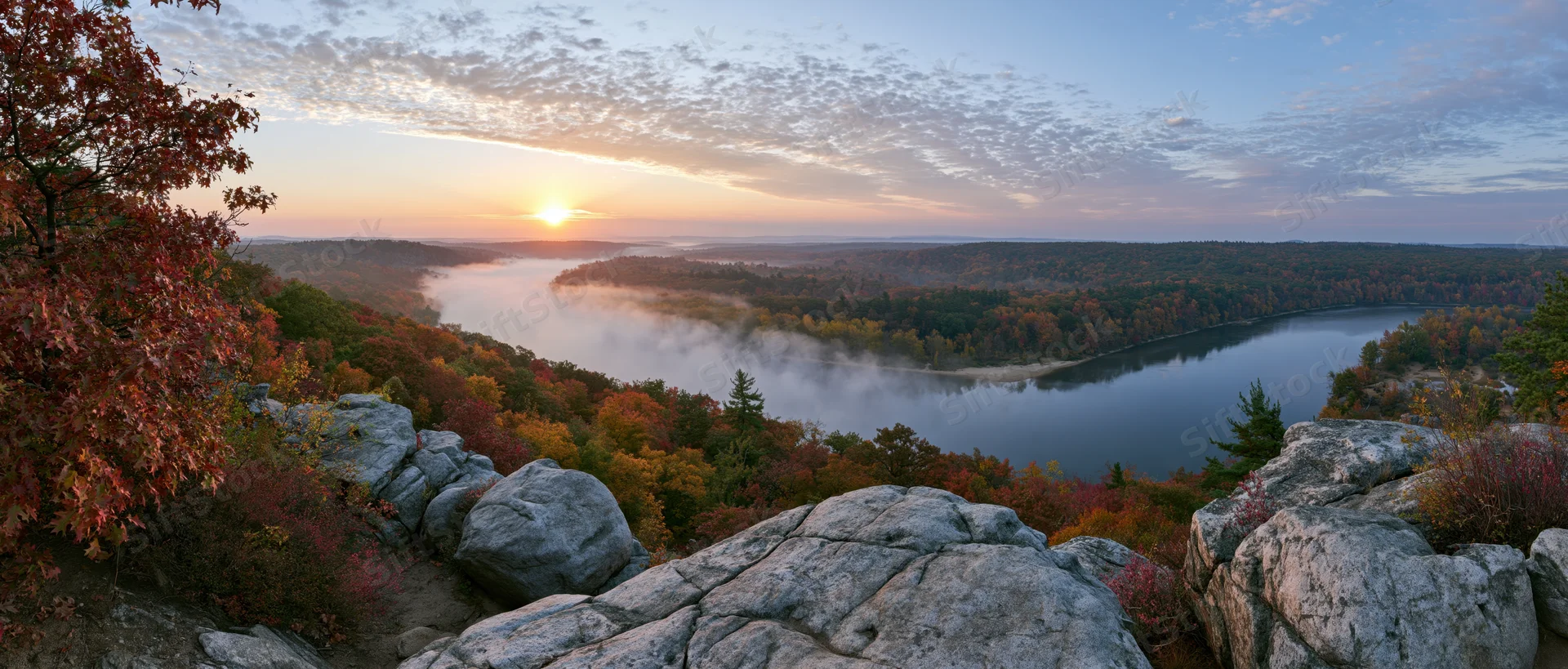 River winding through autumn forest at sunrise viewed from rocky overlook