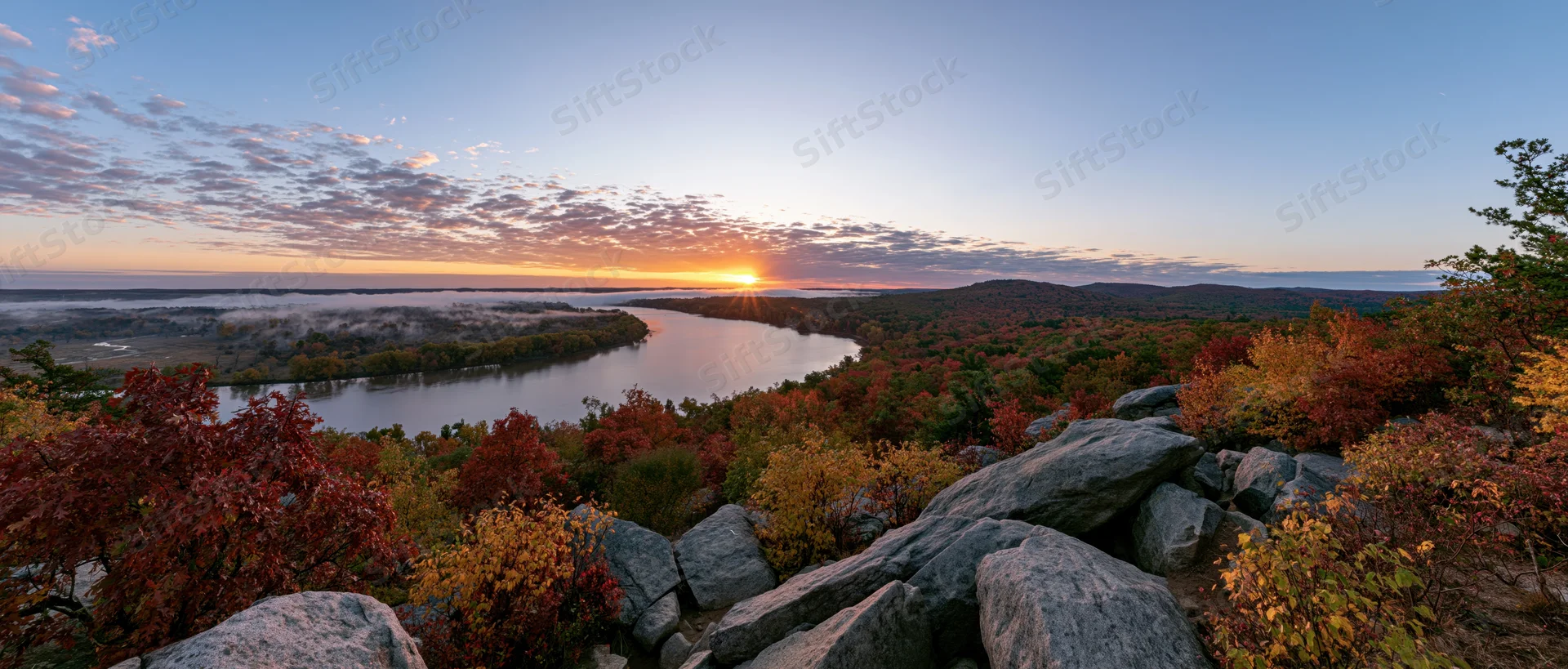 Autumn foliage along a winding river at sunset viewed from rocky overlook