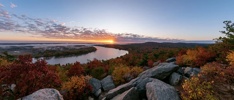 Autumn foliage along a winding river at sunset viewed from rocky overlook