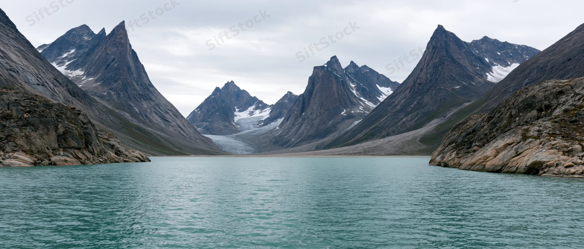 Alpine lake surrounded by snow-capped mountains and glaciers in a remote valley