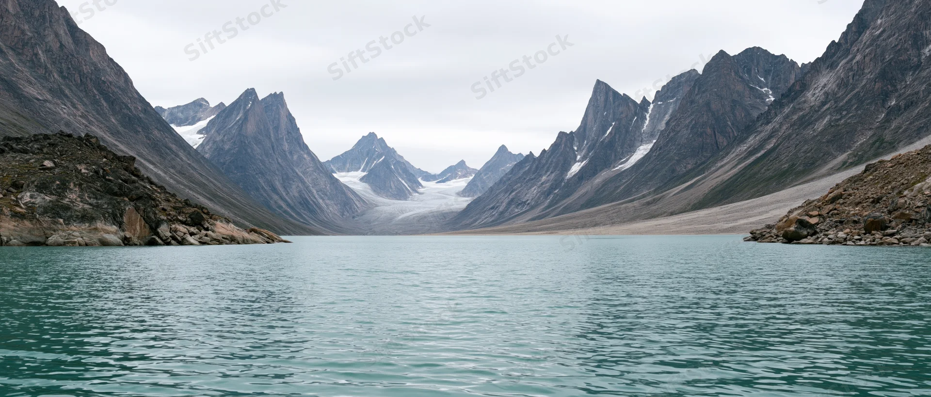 Turquoise lake nestled between jagged alpine peaks with a glacier in the valley beyond