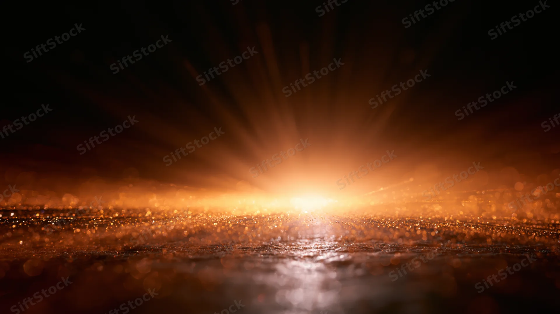 Sunrise over water with glowing rays and bokeh reflections on the surface