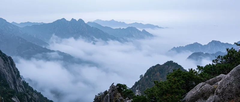 Mountain peaks rising above a sea of clouds in a misty alpine landscape