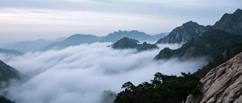 Rocky mountain peaks rising above a sea of clouds in a misty valley