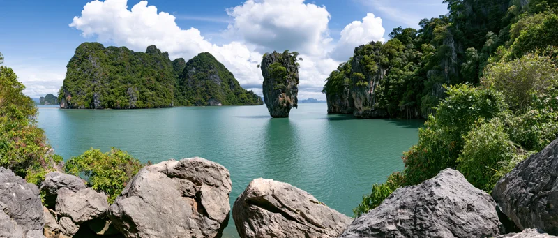 Limestone karst islands rising from turquoise sea in tropical bay surrounded by dense jungle