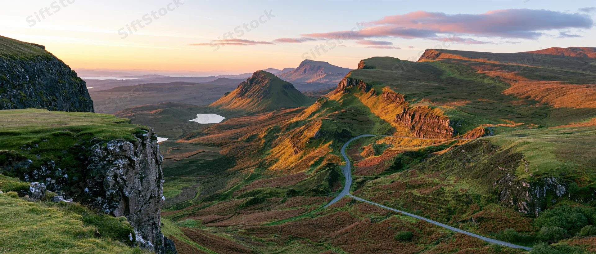 Winding road through mountainous valley at sunset in scottish highlands
