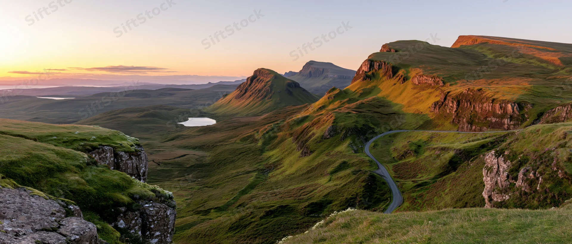 Winding road through green hills and valleys at sunset in the Scottish Highlands