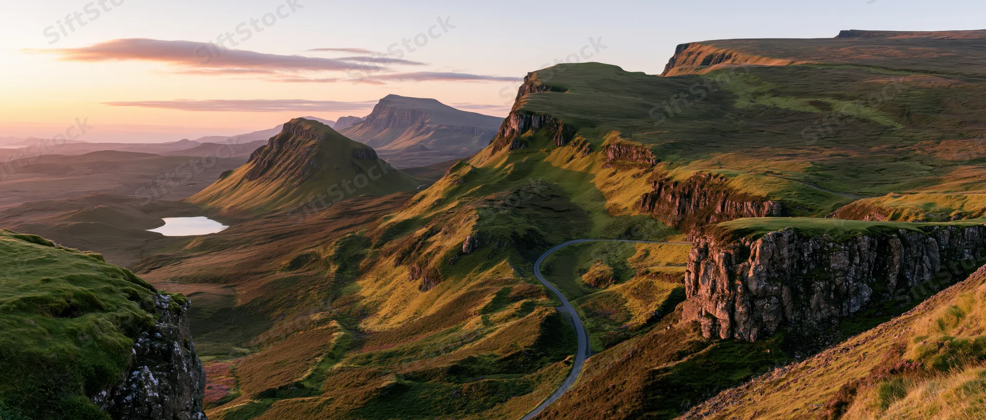 Winding road through green hills and cliffs in a mountain valley at sunset