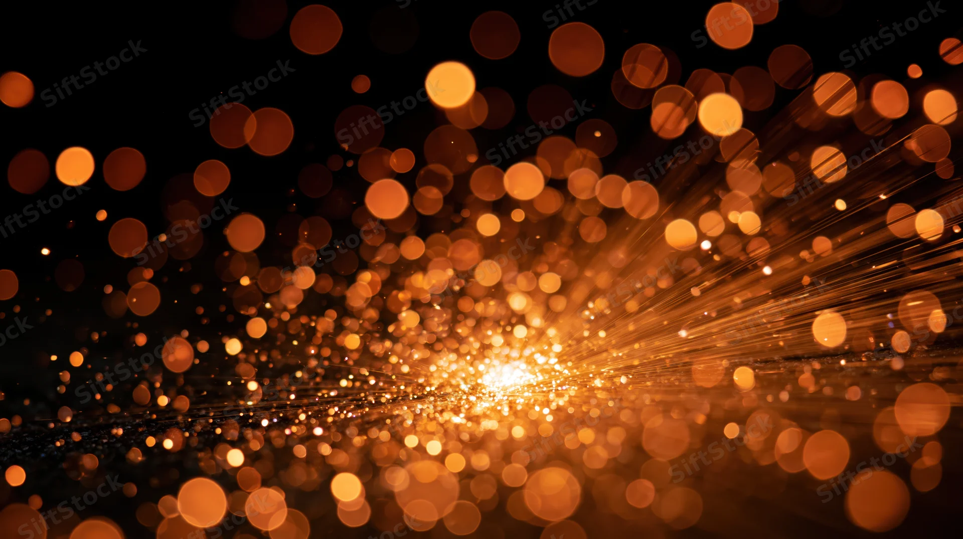 Golden bokeh lights radiating outward in abstract background with soft glow and sparkling particles