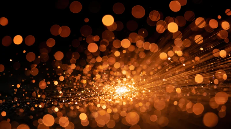Golden bokeh lights radiating outward in abstract background with soft glow and sparkling particles