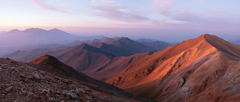 Rugged mountain ridges bathed in warm sunset light overlooking a vast desert valley