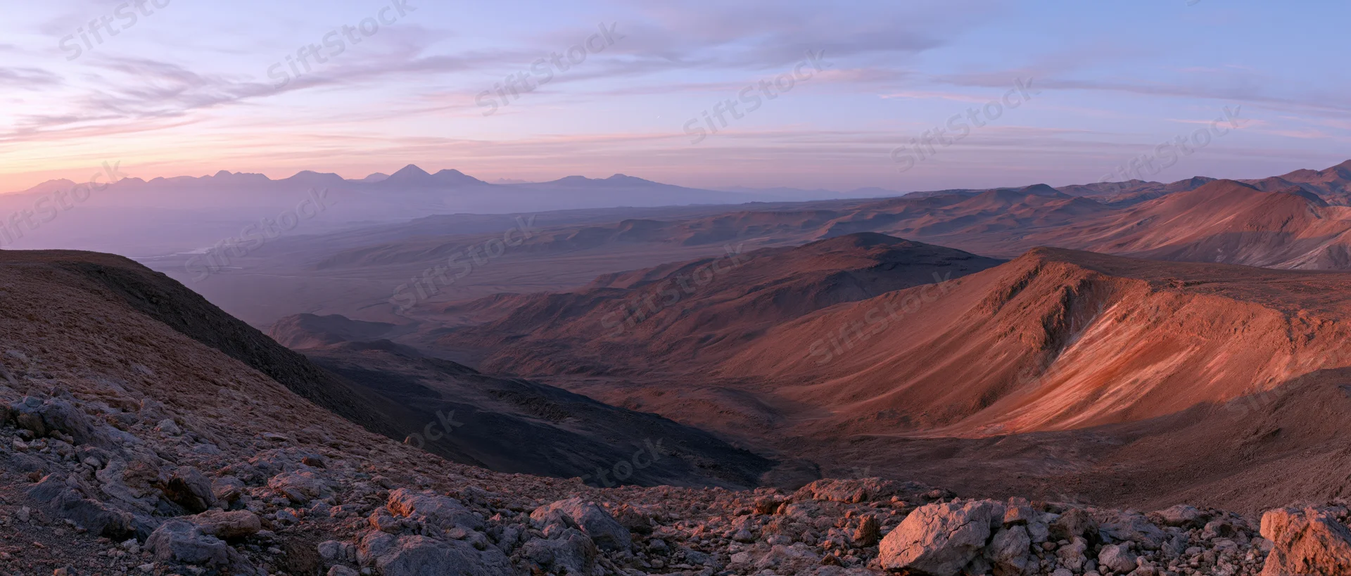 Panoramic view of arid desert valley with layered mountains at sunset