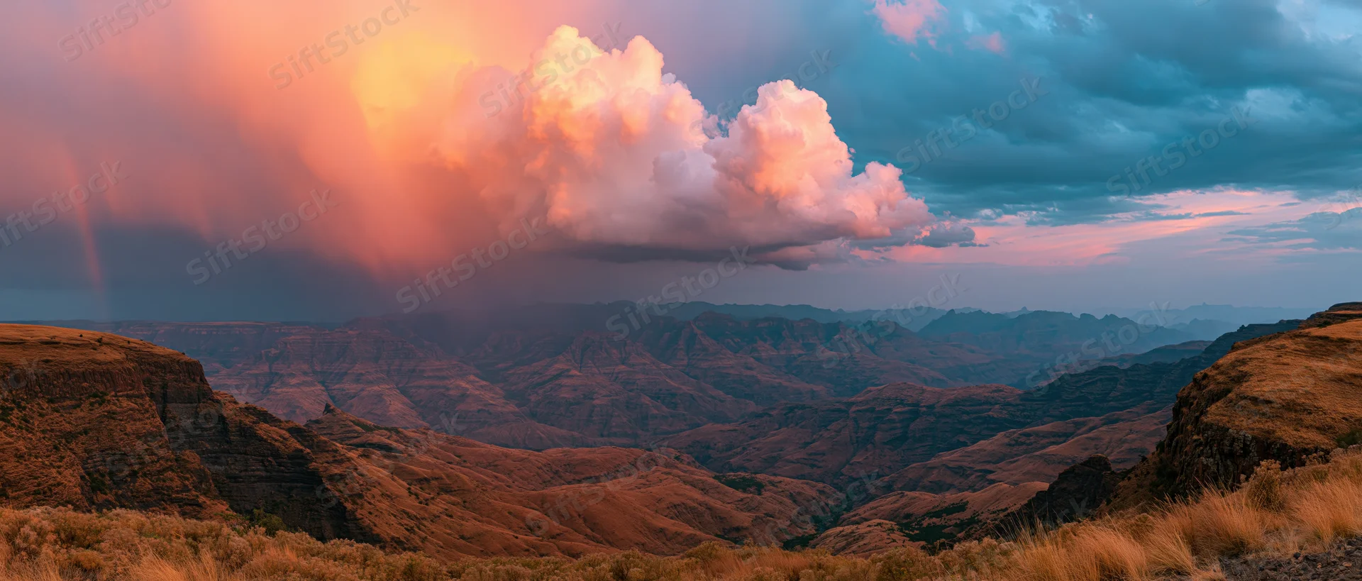 Rugged canyon landscape at sunset with layered rock formations and colorful clouds above