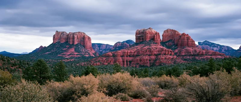 Red rock buttes rising from desert landscape under cloudy sky