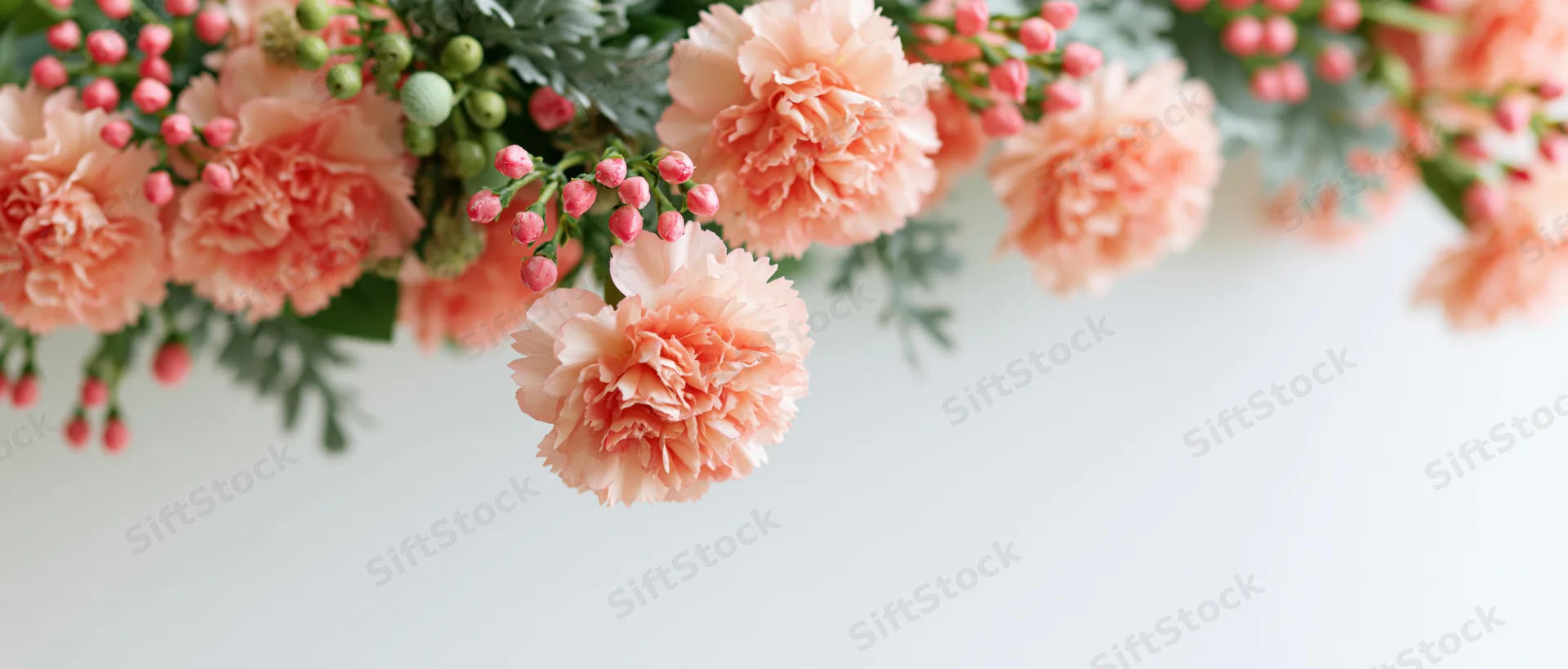 Peach carnations and green foliage arranged in a floral bouquet with copyspace on white background