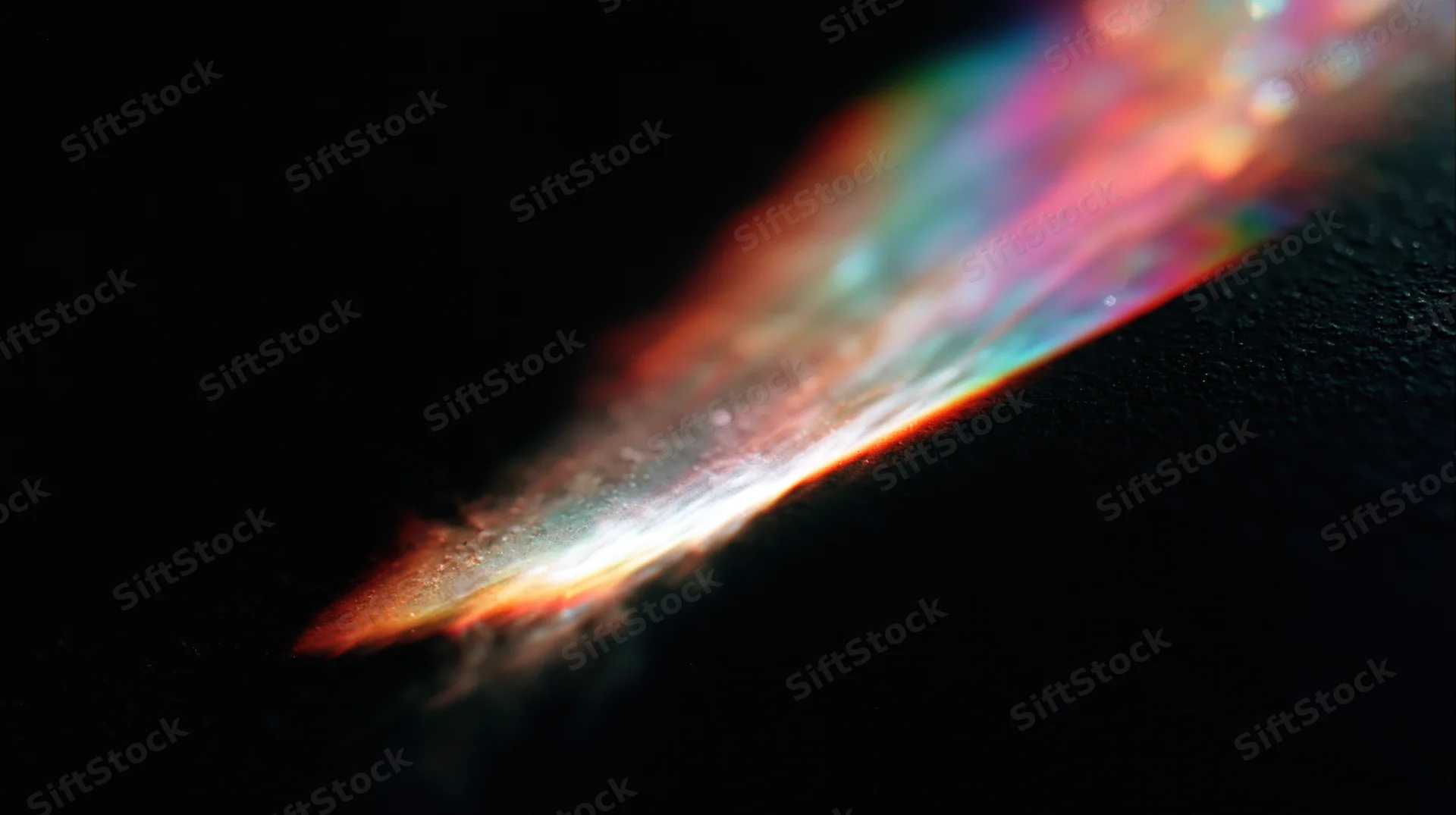 A diagonal beam of rainbow light refracting across a dark textured surface