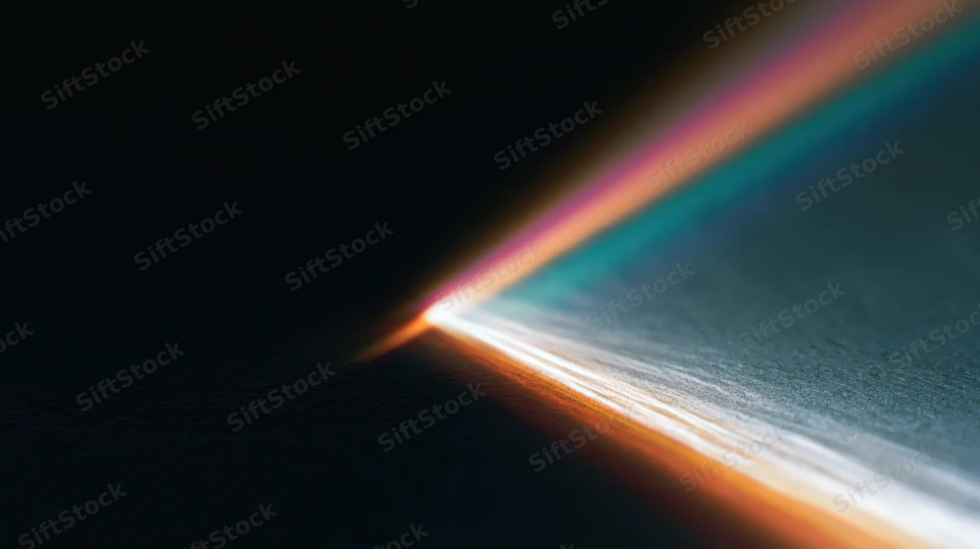 A beam of white light refracting into a spectrum of colors on a dark surface corner
