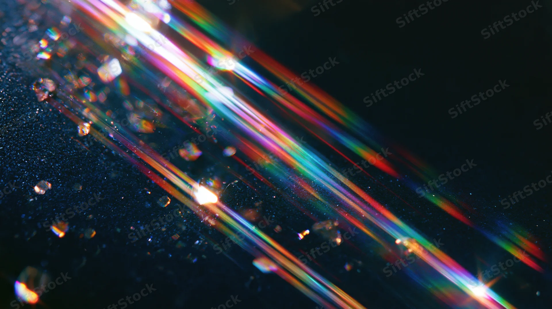 Colorful light beams refracting through water droplets on a dark surface