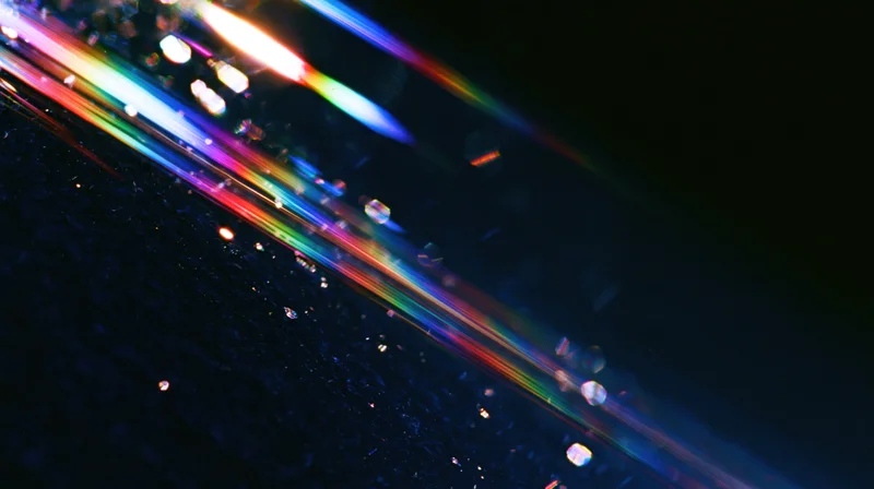 Colorful light streaks refracting across a dark surface with bokeh highlights