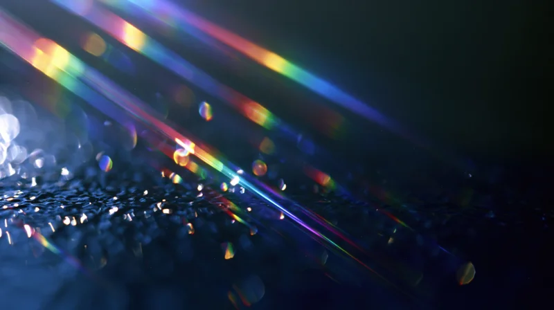 Colorful light beams refracting across a dark textured surface with bokeh highlights