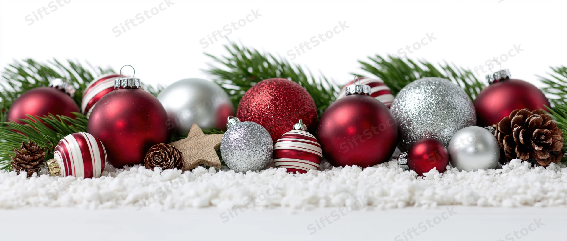 Christmas ornaments arranged with pine branches and pinecones on artificial snow