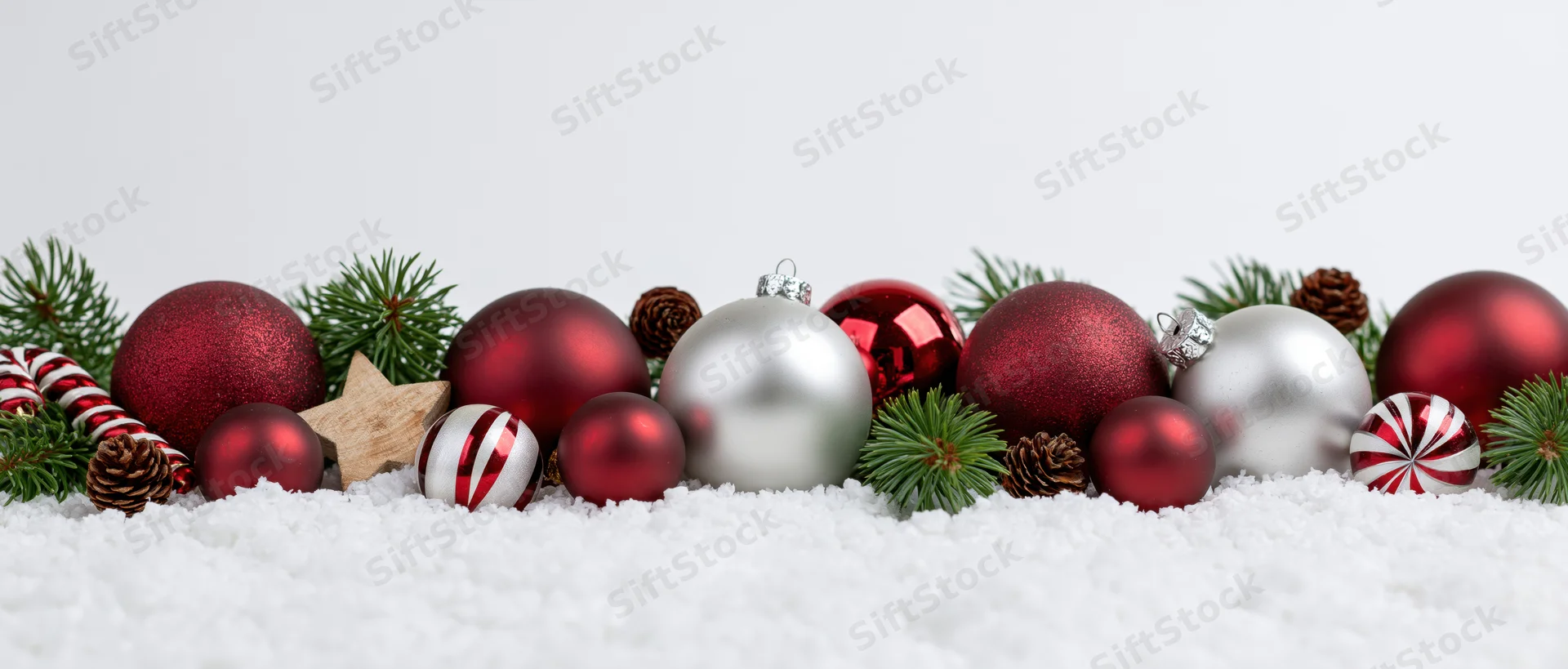Christmas ornaments arranged in snow with pine branches and candy canes