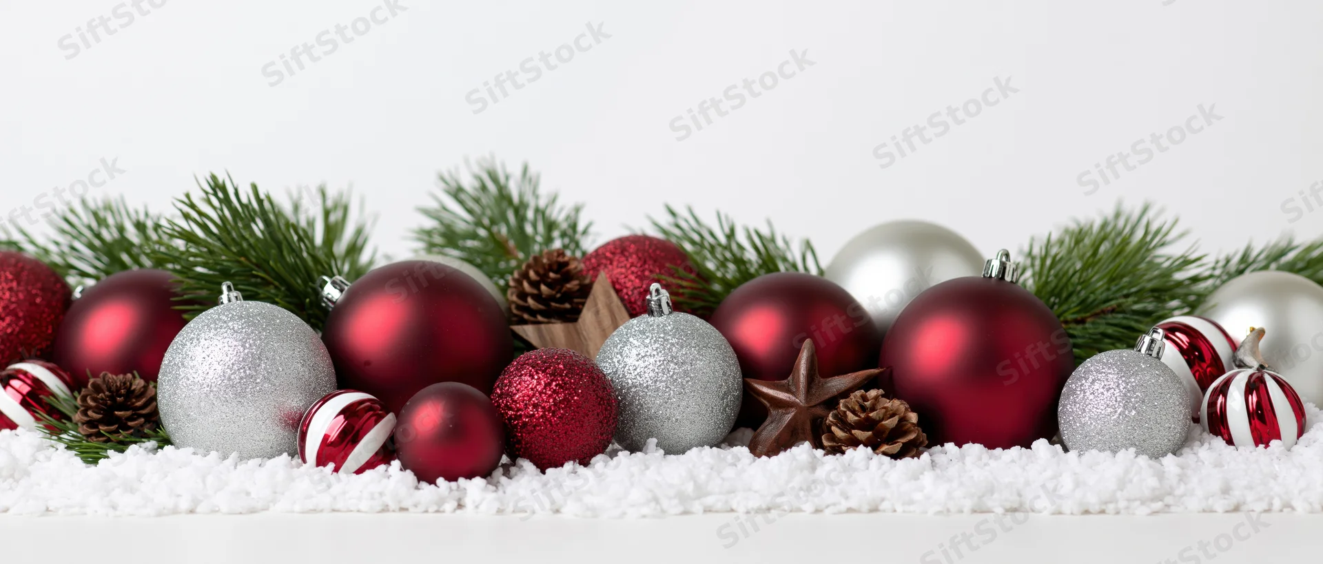 Christmas ornaments and pine branches arranged on snow with copyspace