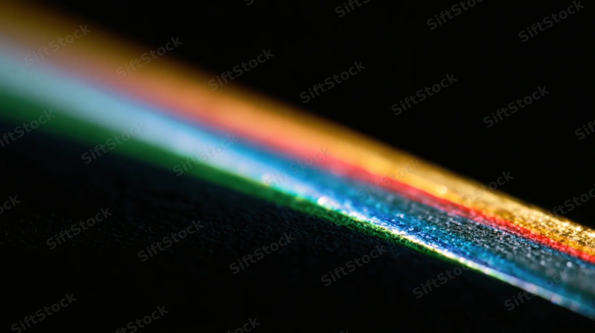 A spectrum of colored light bands refracted across a dark surface