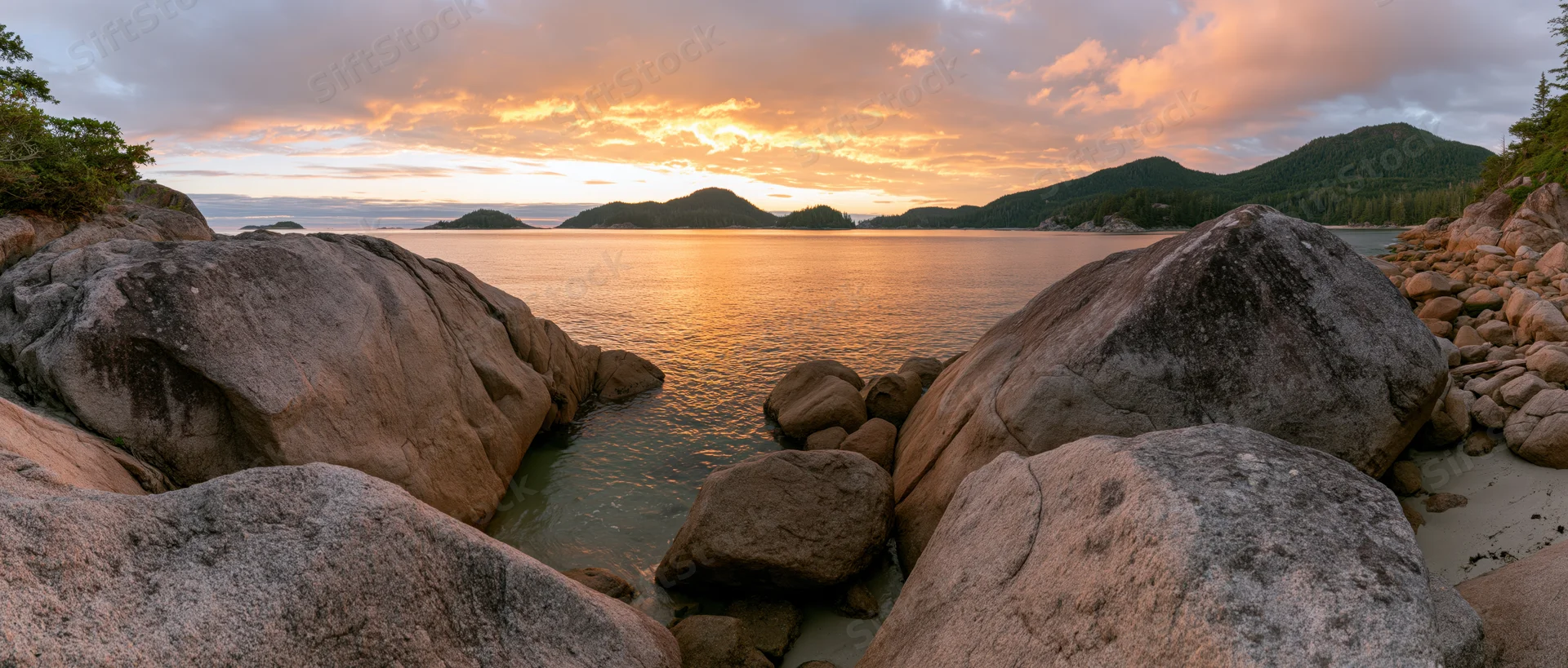 Rocky coastline at sunset with calm ocean and distant mountains