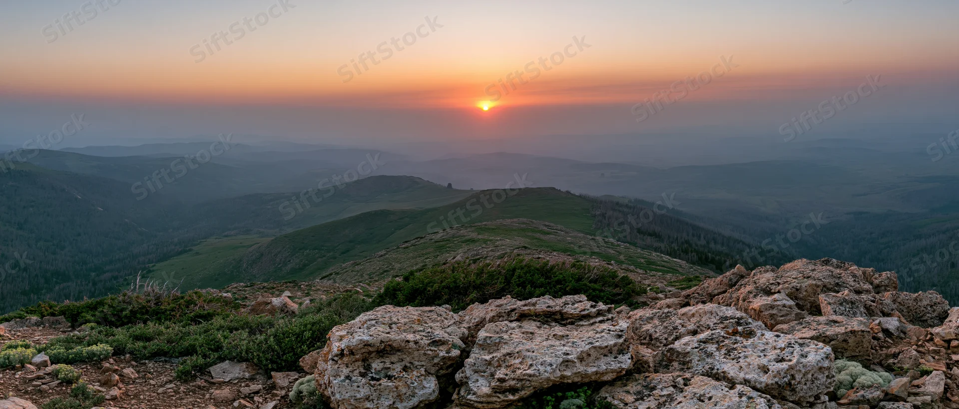 Mountain ridge at sunset overlooking layered valleys and forests
