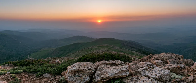 Mountain ridge at sunset overlooking layered valleys and forests