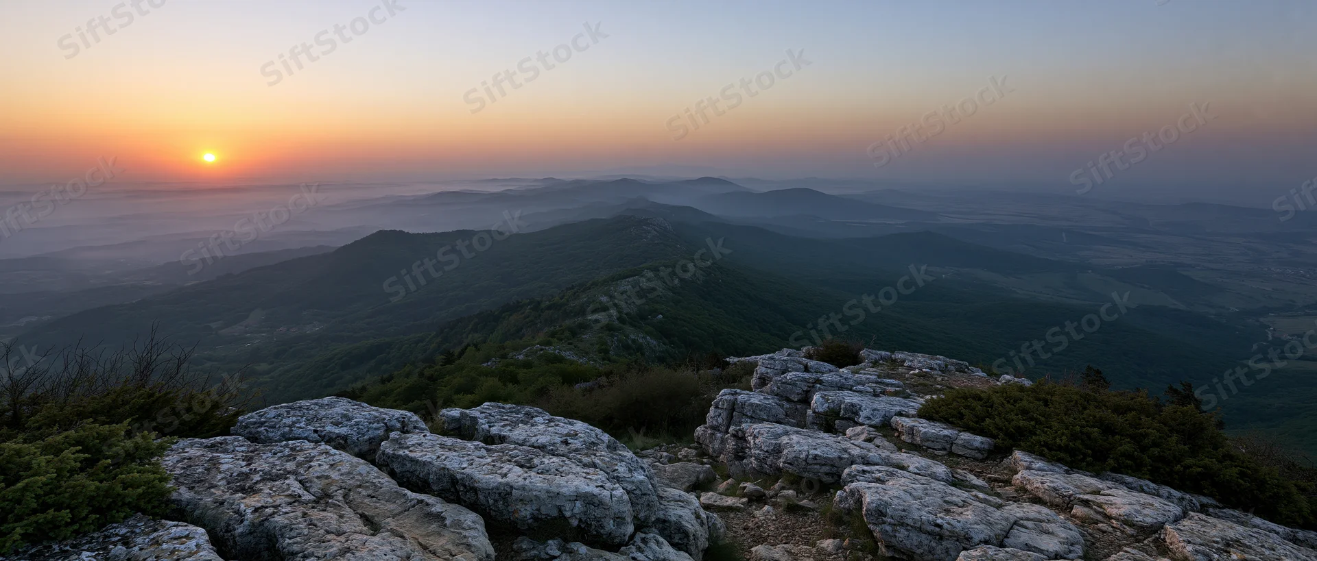 Rocky mountain peak overlooking a misty valley at sunset