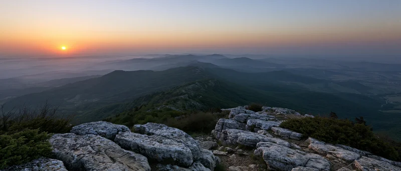 Rocky mountain peak overlooking a misty valley at sunset