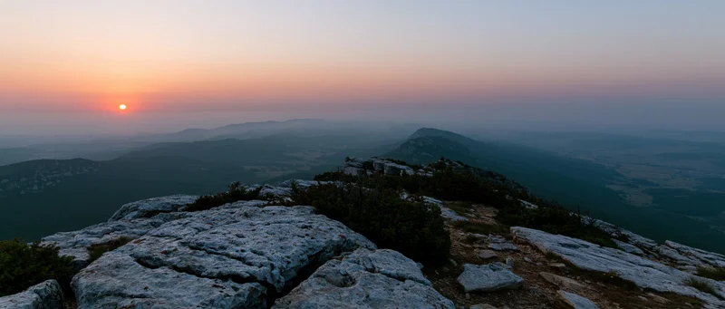Rocky mountain peak overlooking a hazy valley at sunset