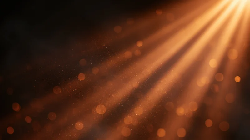 Golden light rays shining through dust particles in a dark space with bokeh highlights