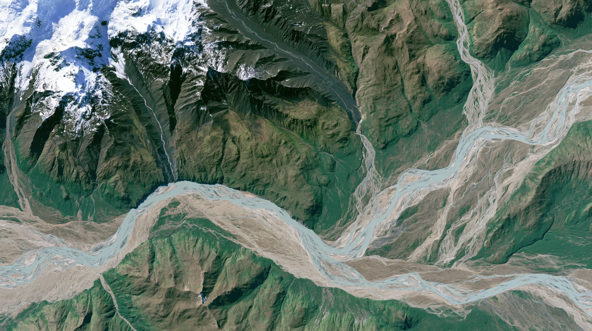 Winding river flowing through mountain valley with snow-capped peaks and glacial sediment
