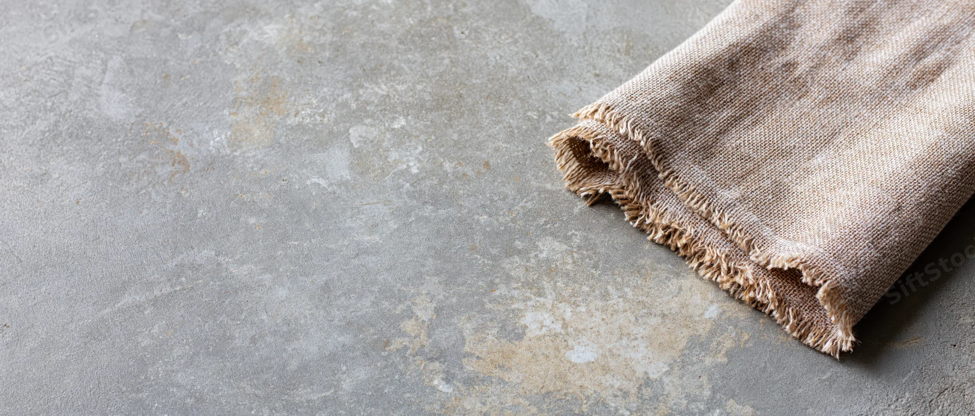 Folded linen cloth on textured concrete surface with copyspace
