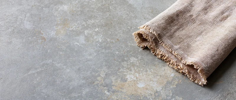 Folded linen cloth on textured concrete surface with copyspace