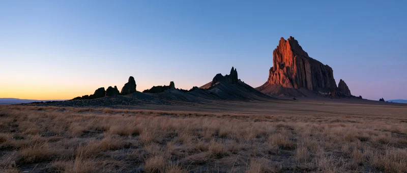 Red rock butte formation rising from arid desert plain at sunset