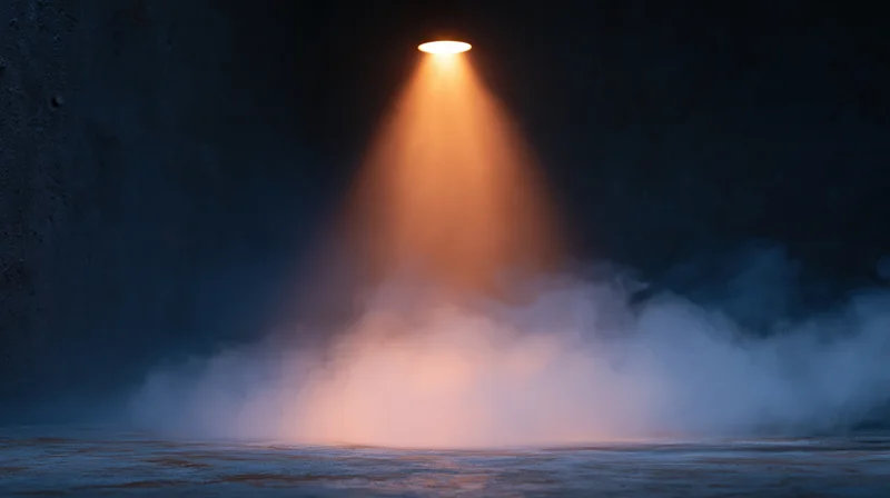 Spotlight beam illuminating fog over dark water surface in cave-like setting