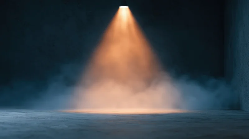 Warm spotlight beam illuminating smoke in dark empty industrial space