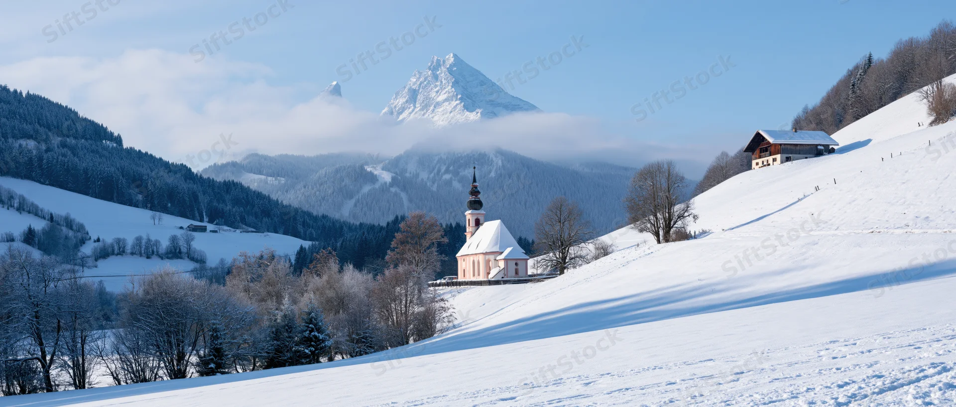 Snow-covered church nestled in alpine valley with mountain peak in background